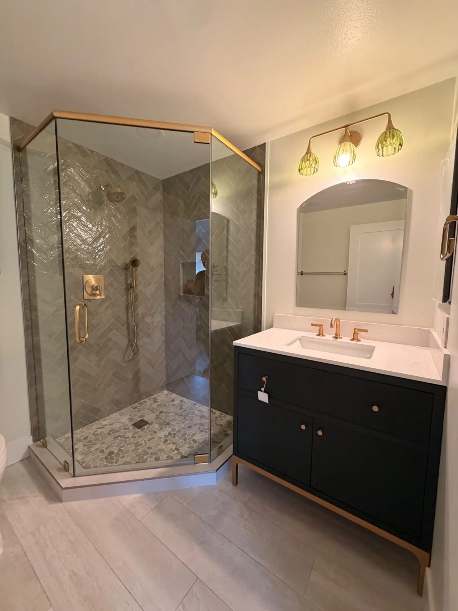 Completed bathroom remodel with herringbone tile and frameless glass in Laguna Beach